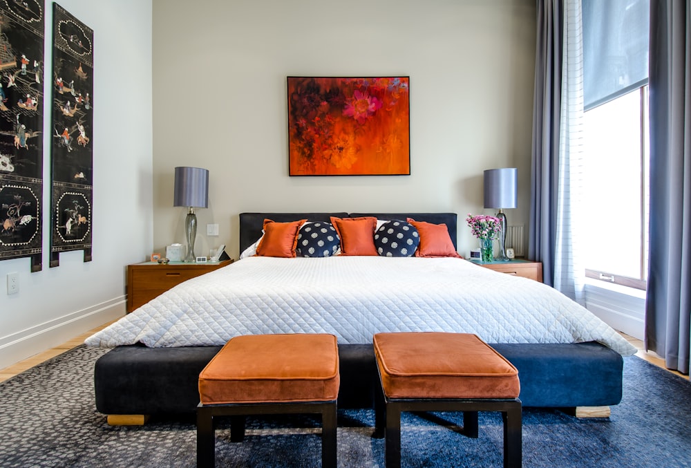 Elegant master bedroom interior with upholstered cream headboard, decorative chandelier, warm bedside lamps, throw cushions, and large windows — luxury finishes at Niharika Independent Floors